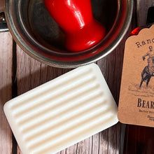 Bar of soap next to a can of red paint on a wooden surface with a branded card.