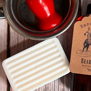 Bar of soap next to a can of red paint on a wooden surface with a branded card.