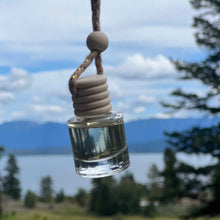 Glass bottle with wooden top hanging against a scenic background of mountains and trees.