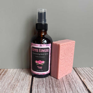 Hippie Cowgirl moisturizing body spray and pink soap on a wooden surface with a gray background